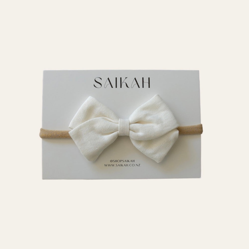 
                  
                    White linen baby bow headband on white card
                  
                